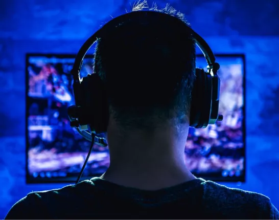Back of man's head wearing headphones in front of a computer screen