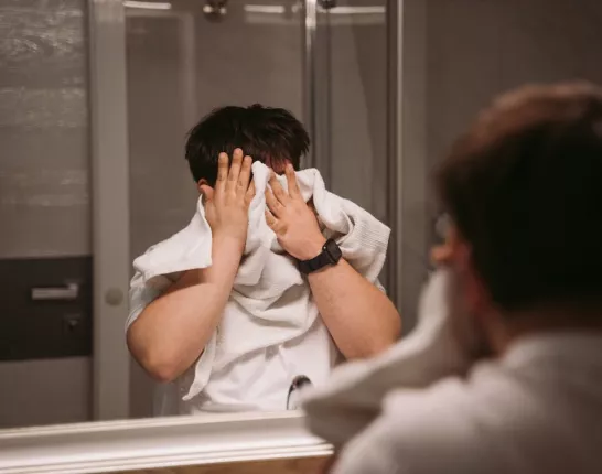 Man in the bathroom tries to wipe his face off with towel
