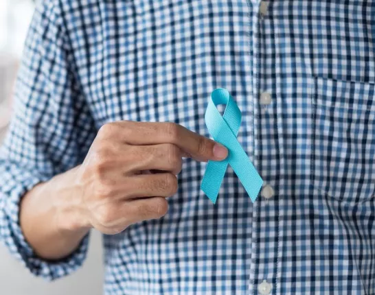 A man holding a blue ribbon for prostate cancer awareness