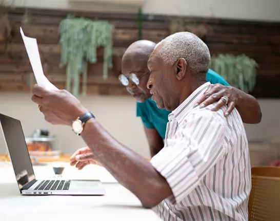 A black couple looking over paperwork and at a laptop