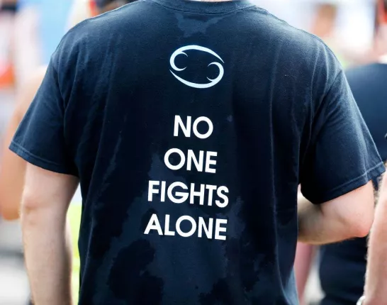 Man wearing a sweaty black t-shirt that says 'No one fights alone'