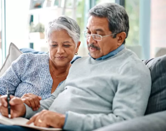 Senior hispanic couple sitting together on a couch writing