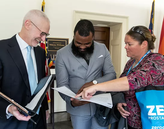 Three advocates looking at papers inside of folders at the Capitol 