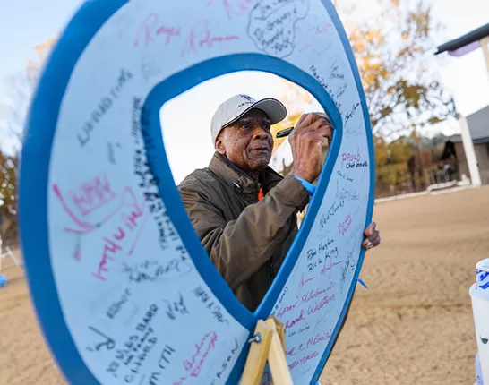 Black man signing a giant blue ribbon sign