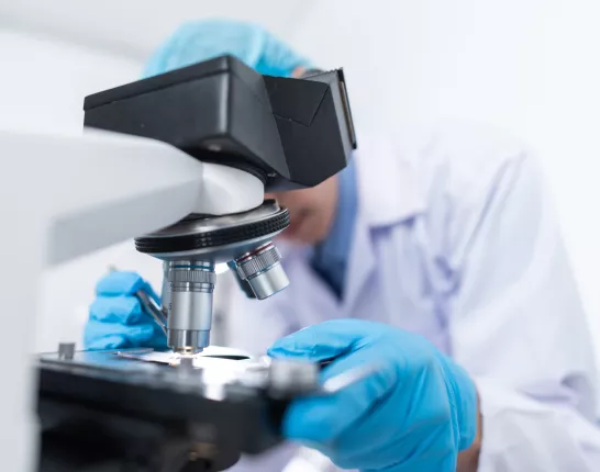 Scientist looking into microscope for prostate cancer research