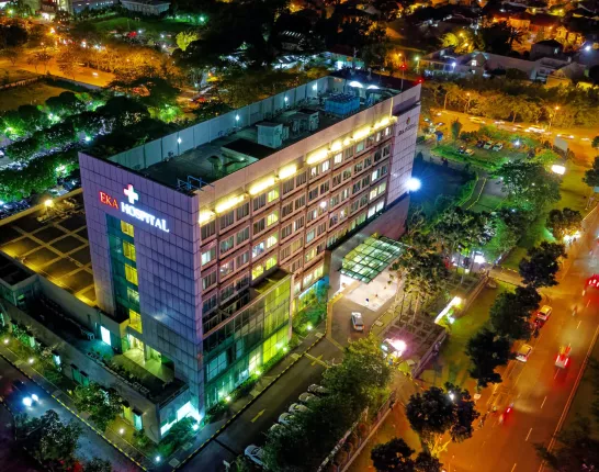 A hospital in a city at night time with many sources of bright colored lights