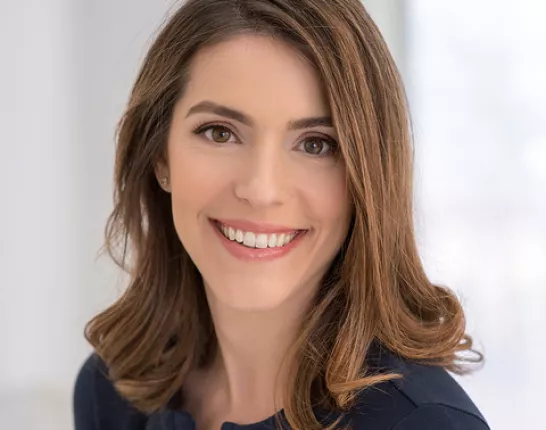 A young woman with brown, wavy hair posing for her headshot