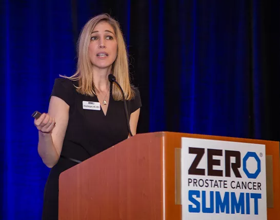 A blonde woman in a black dress behind the podium at Summit