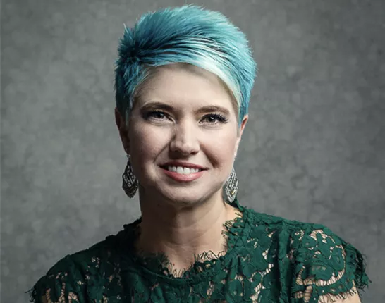 A woman with short blue hair and a green dress