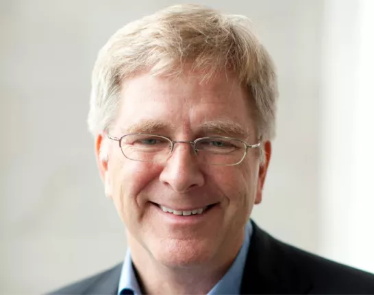 An older man in a suit with blonde hair and glasses