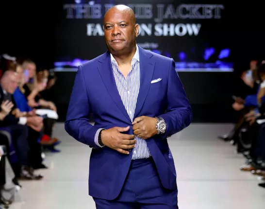 A Black man wearing a blue suit on the runway of the Blue Jacket Fashion Show