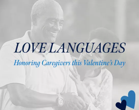 A promotional banner for ZERO Prostate Cancer featuring the text "LOVE LANGUAGES" in dark blue capital letters, with "Honoring Caregivers this Valentine's Day" in light blue script below. The background shows a soft, grayscale image of what appears to be a caregiver interaction. The ZERO Prostate Cancer logo appears in the bottom left corner, and two hearts (one dark blue, one light blue) are positioned in the bottom right corner.