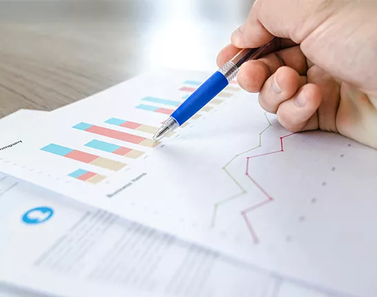hand holding pen over paper with graph