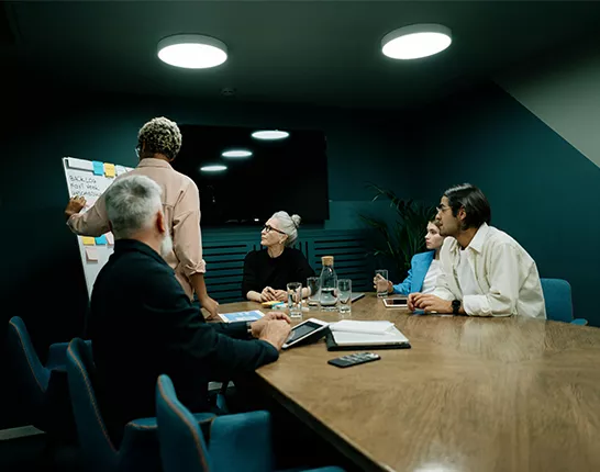 Group of people at desk at work looking at presenter