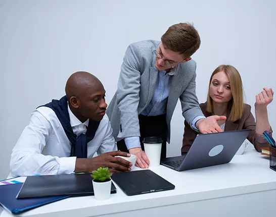 group of 3 people at table talking in office clothes