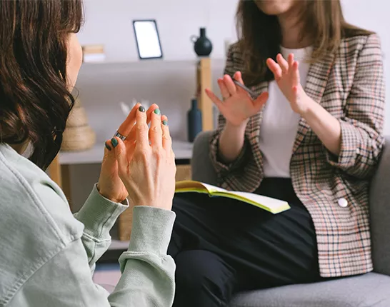 two women sitting, one with a yellow notepad