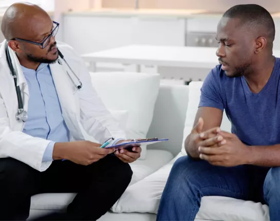 A doctor consults with a patient on a couch, discussing important health information in a calm, supportive setting