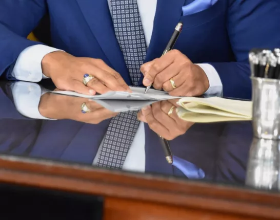 Hands of a man signing a piece of paper