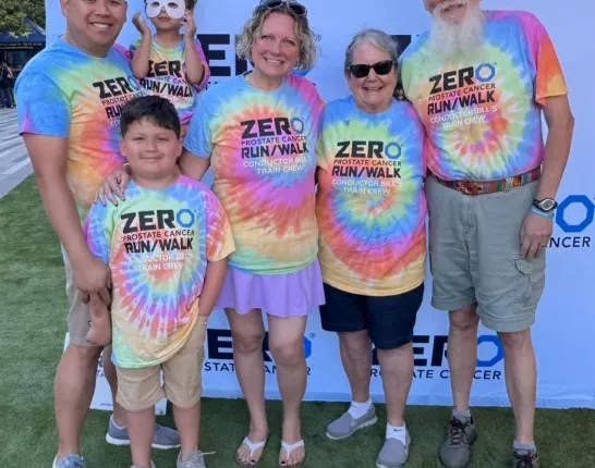 Picture of Elizabeth with family in tie dye shirts in front of ZERO banner