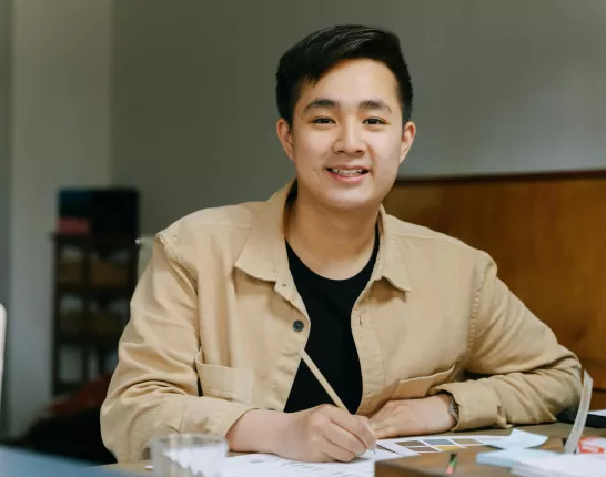 asian man smiling sitting at desk