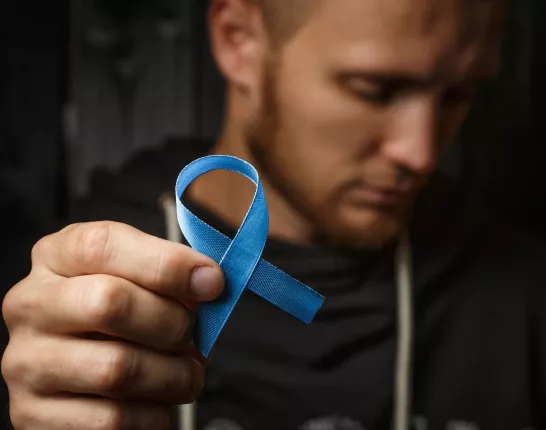 Man holding blue ribbon in forefront of image