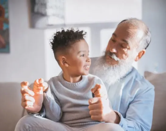 Man sitting on couch with small child on lap smiling at each other