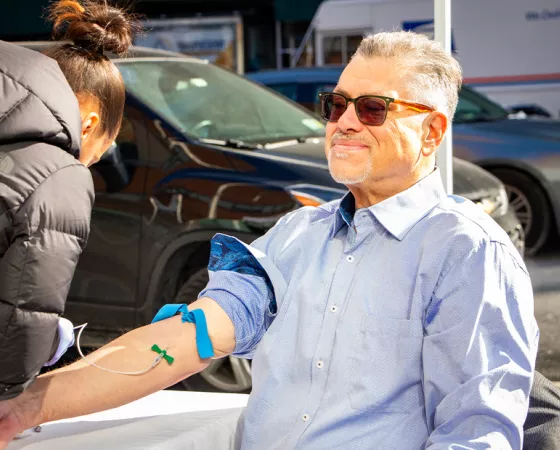 A man sitting in a chair with his arm in a tourniquet for a blood test.
