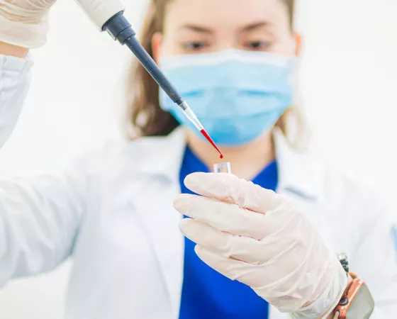 Woman in a Lab Coat Holding a Test Tube