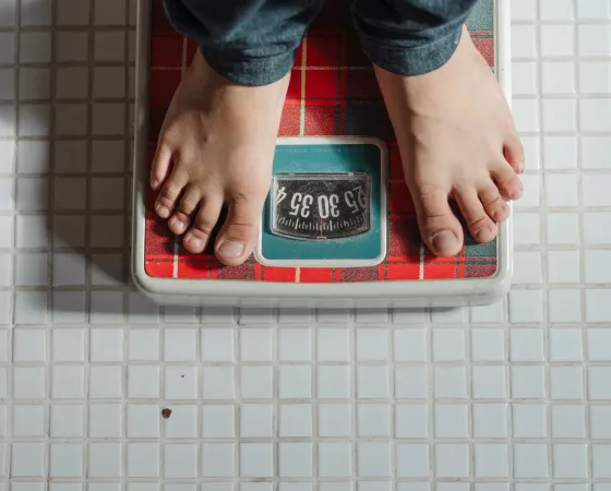 Crop kid weighing on red scale