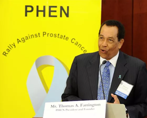 Thomas A. Farrington speaking at a podium with a PHEN sign behind him