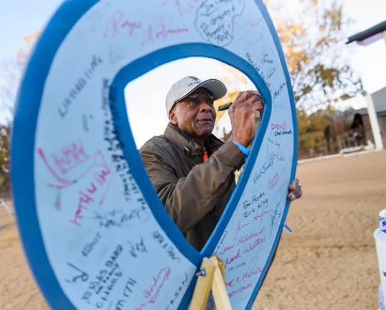 Black man signing a giant blue ribbon sign