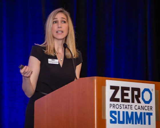 A blonde woman in a black dress behind the podium at Summit