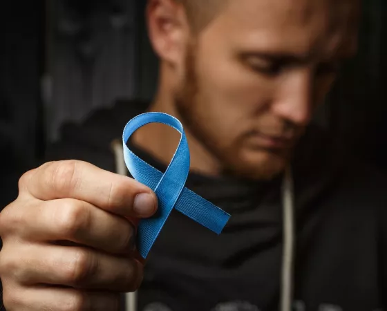 Man holding blue ribbon in forefront of image