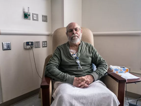 A man sitting in a chair in the hospital receiving chemotherapy treatment