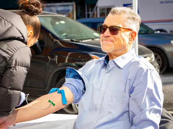 A man sitting in a chair with his arm in a tourniquet for a blood test.