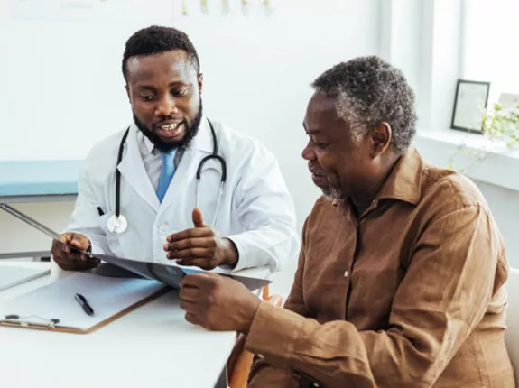 A Black man talking to his doctor at a desk