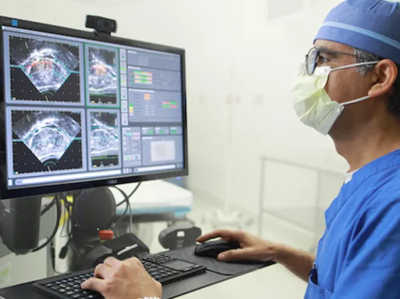 Doctor standing at computer looking at ultrasound images