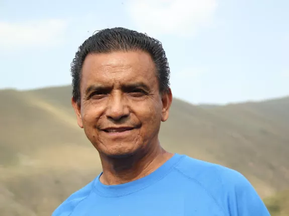 Latin man in blue shirt standing in front of barren mountains