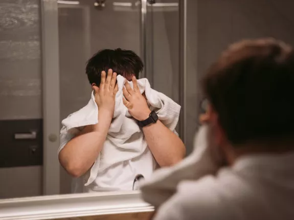 Man in the bathroom tries to wipe his face off with towel