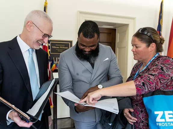 Three advocates looking at papers inside of folders at the Capitol