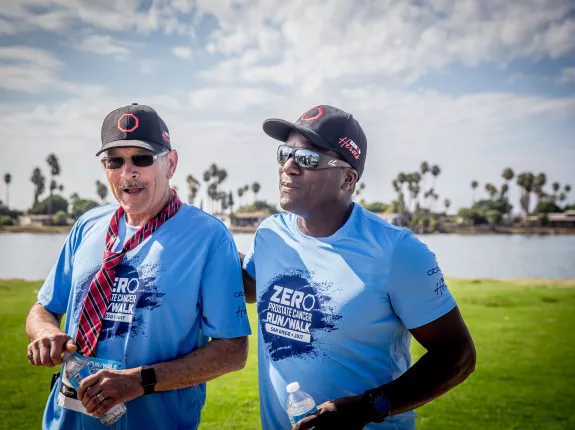 Two men in blue t-shirts and baseball hats