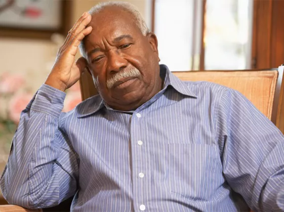 An older black man with his head on his hand as he slumps in a chair