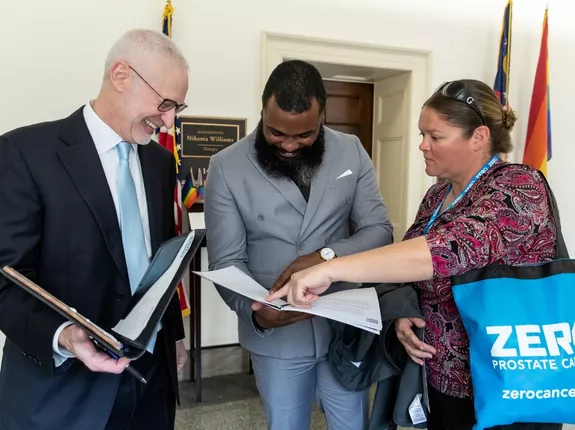 Two men and a woman looking a book in a legislative hall