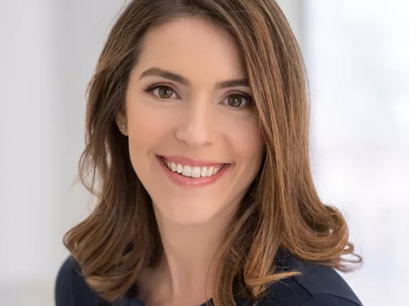 A young woman with brown, wavy hair posing for her headshot