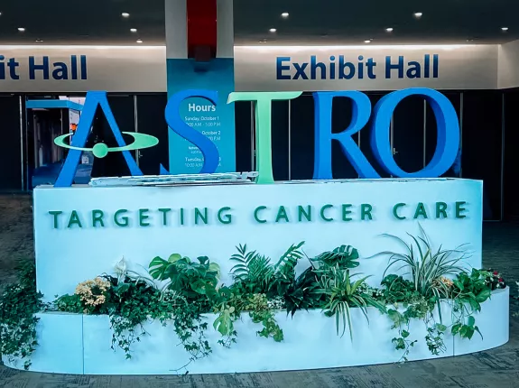 A sign at a conference with big letters spelling "ASTRO" and the base says "Targeting Cancer Care"