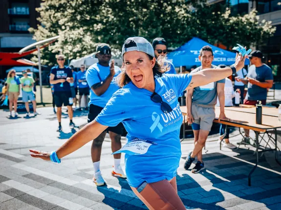 A woman with a backwards hat wearing a Run/Walk shirt standing with her arms out in a silly position