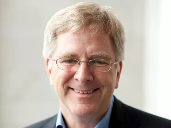 An older man in a suit with blonde hair and glasses