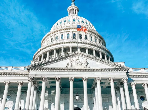 The U.S. Capitol building under a clear blue sky, featuring its iconic dome and American flag.