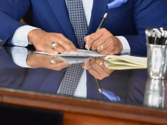 Hands of a man signing a piece of paper