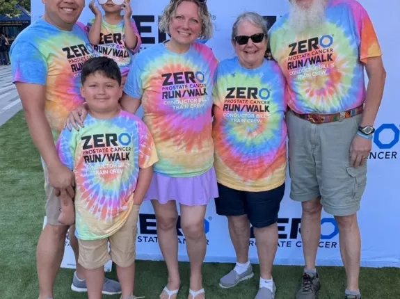 Picture of Elizabeth with family in tie dye shirts in front of ZERO banner